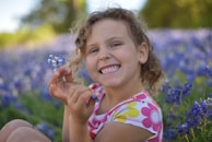 A portrait of a smiling child playing in a field of flowers.