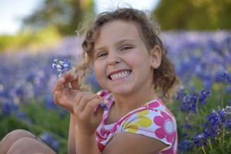 A portrait of a smiling child playing in a field of flowers.