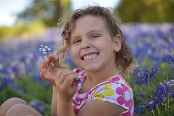 Portrait of a smiling child playing in a field of wildflowers on a sunny day.