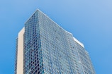 A modern high-rise building reflecting sunlight against a clear blue sky.