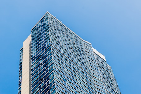 Luxurious high-rise office building with reflective glass facade against a clear sky.