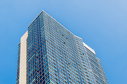 A sleek, modern high-rise building with reflective glass windows under a clear sky.