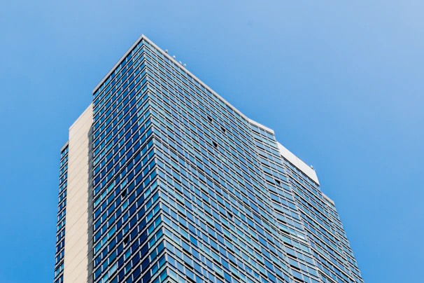 A sleek, modern high-rise building with reflective glass windows under a clear sky.