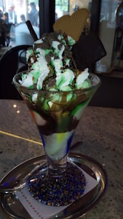 A vibrant sundae topped with fresh strawberries, whipped cream, and a cherry in a clear glass cup.