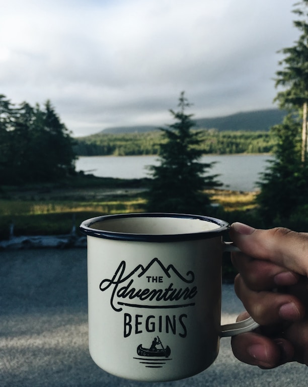 person holding cup with body of water background