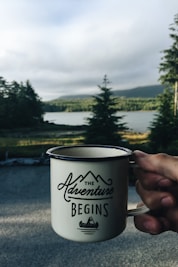 person holding cup with body of water background