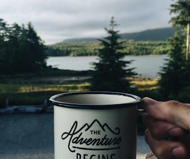 person holding cup with body of water background