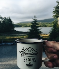 person holding cup with body of water background