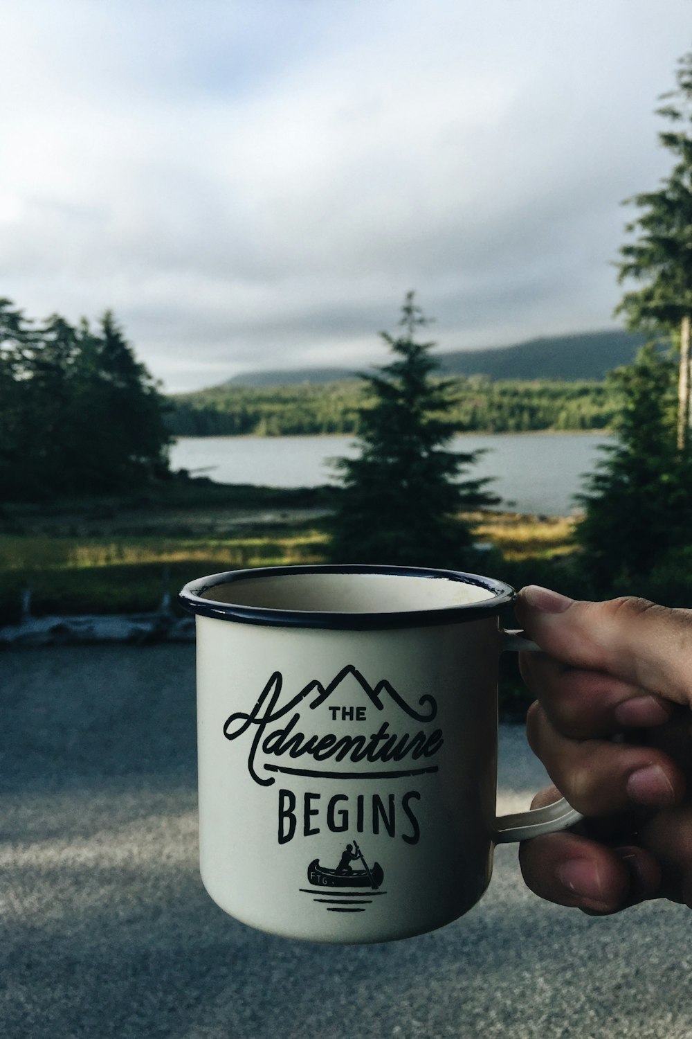 Person mit Becher mit Gewässerhintergrund