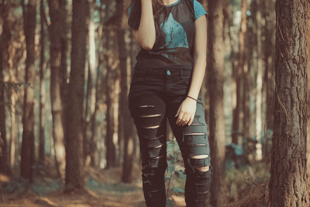 a woman standing in the woods talking on a cell phone