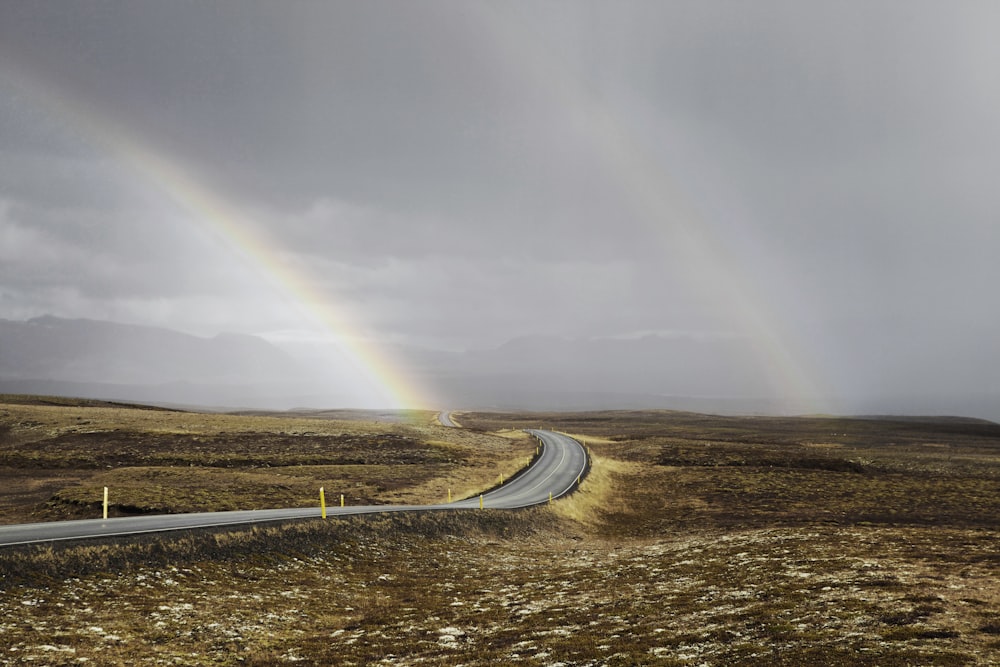 landscape photo of road under the rainbows