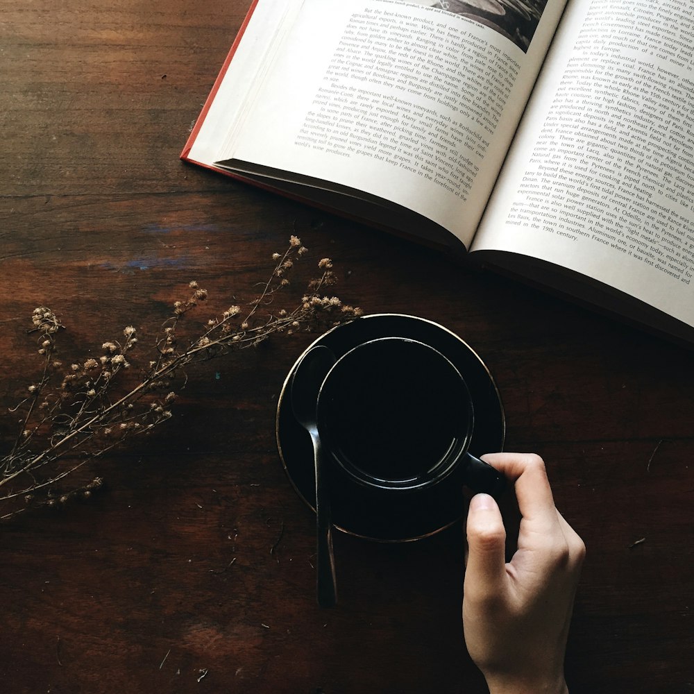 contenitore rotondo in metallo nero vicino al libro bianco aperto