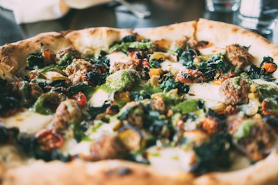 Close-up of a pizza slice topped with pesto-ranch sauce, fresh greens, and melted cheese.