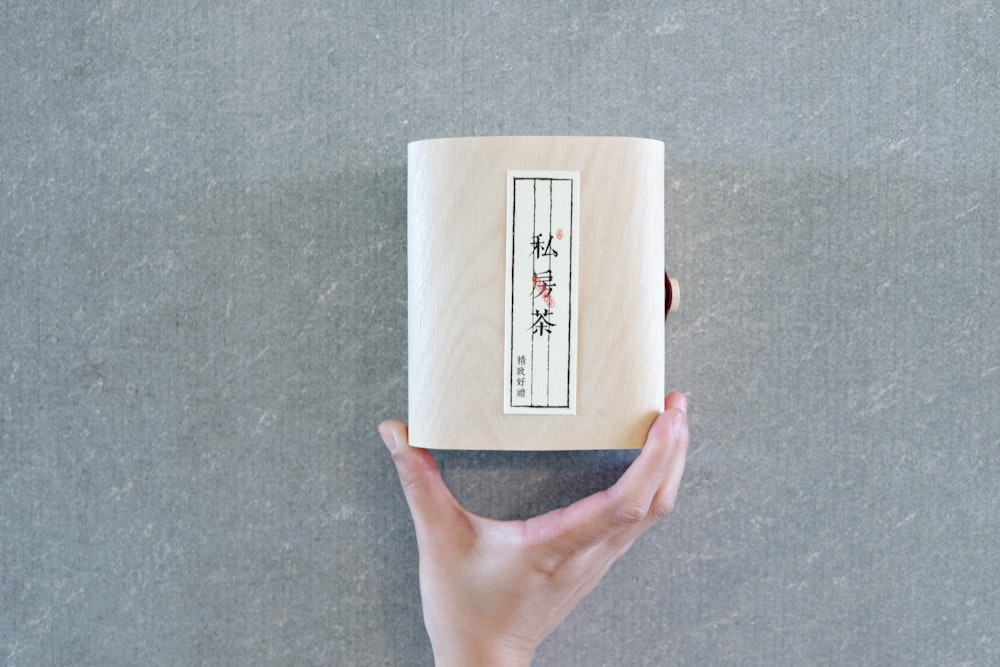 a person holding a wooden box with writing on it