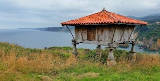 Traditional Asturian horreo granary set against lush green hills on a sunny day.