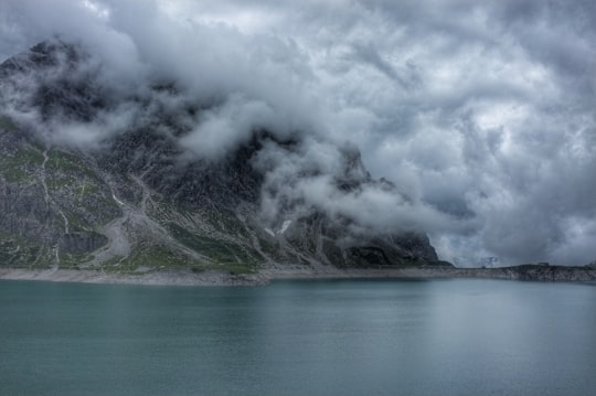 body of water beside mountain covered with fog in Lünersee Austria