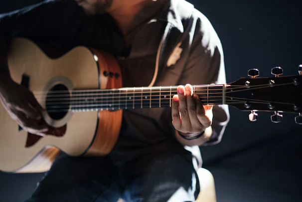Close-up of hands playing an acoustic guitar under warm, cinematic lighting.