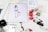 A workspace is filled with feminine fashion illustrations and cosmetic items. Digital drawings are displayed on tablets alongside traditional sketches. Nail polish bottles in various vibrant colors and a Dior makeup box are arranged neatly. The scene blends technology and art in a stylish manner.