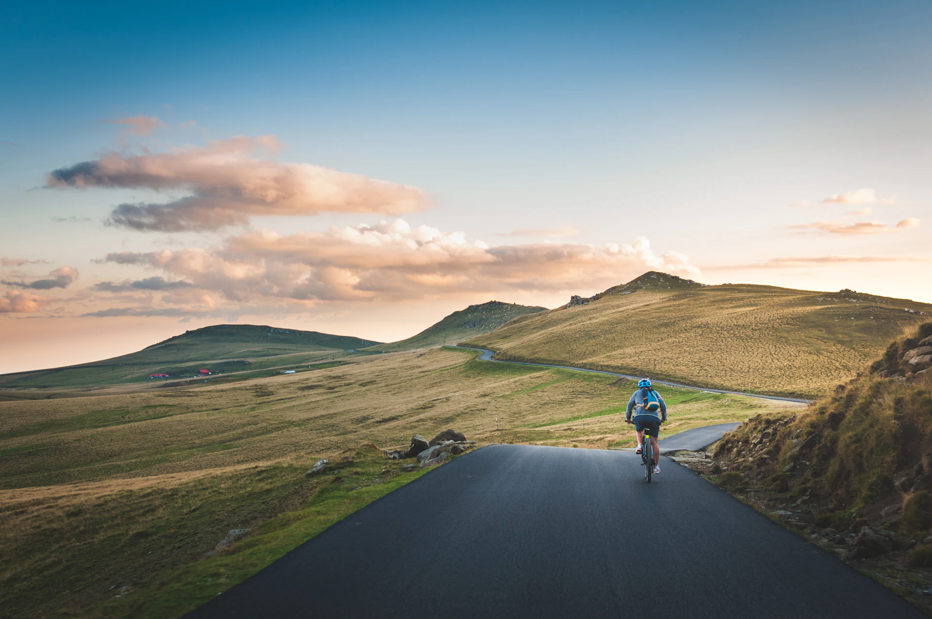 A cyclist riding a mountain road toward the horizon