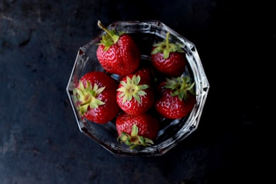 red strawberries in clear glass bowl berry teams background