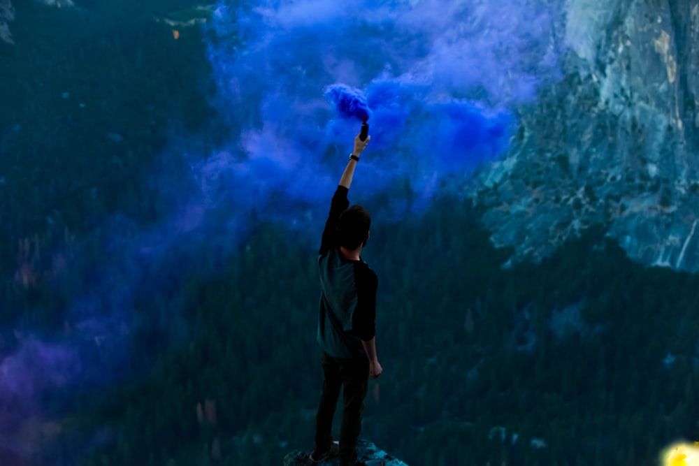 man holding blue powder while raising hand