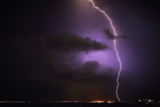 A dramatic lightning bolt striking against a dark stormy sky.