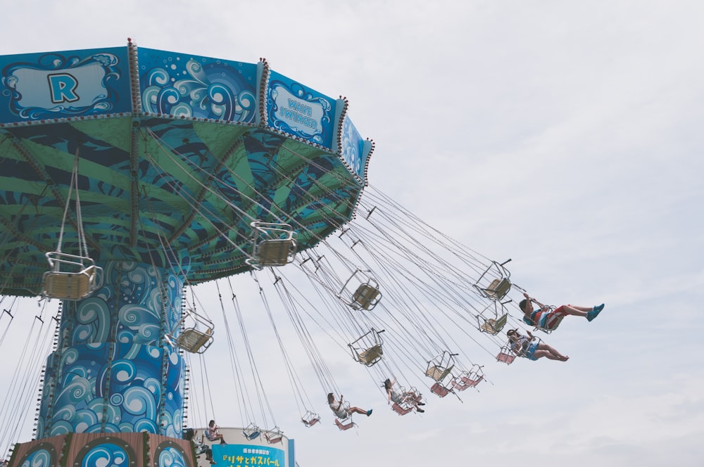 a blue and green carnival ride with people on it