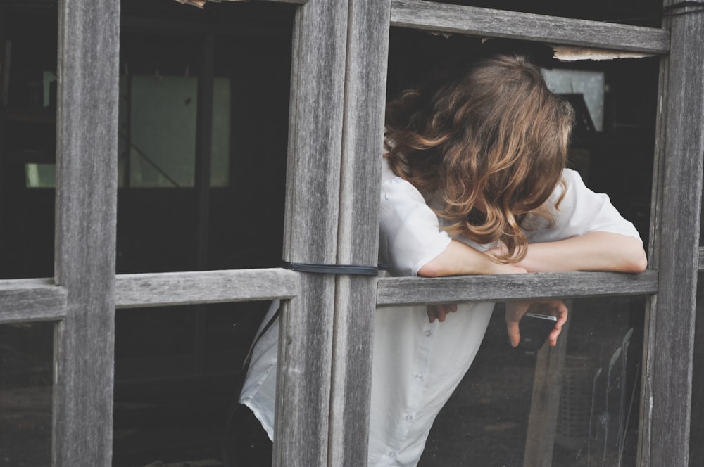 Frau lehnt sich an Fenster