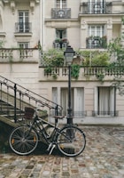 bike leaning against handrail in front of concrete building at daytime