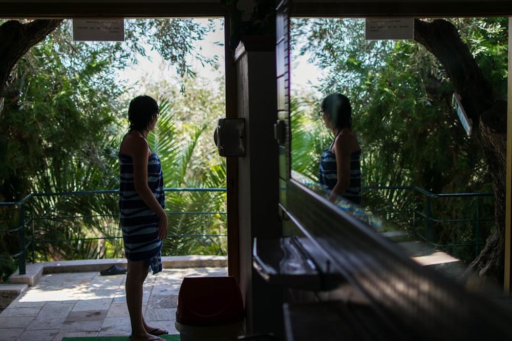 woman standing near door facing trees during daytime