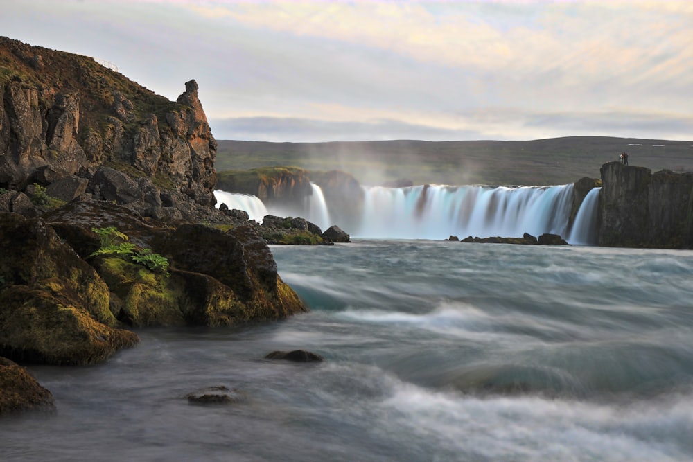 waterfalls on brown rocky mountain under white sky during daytime