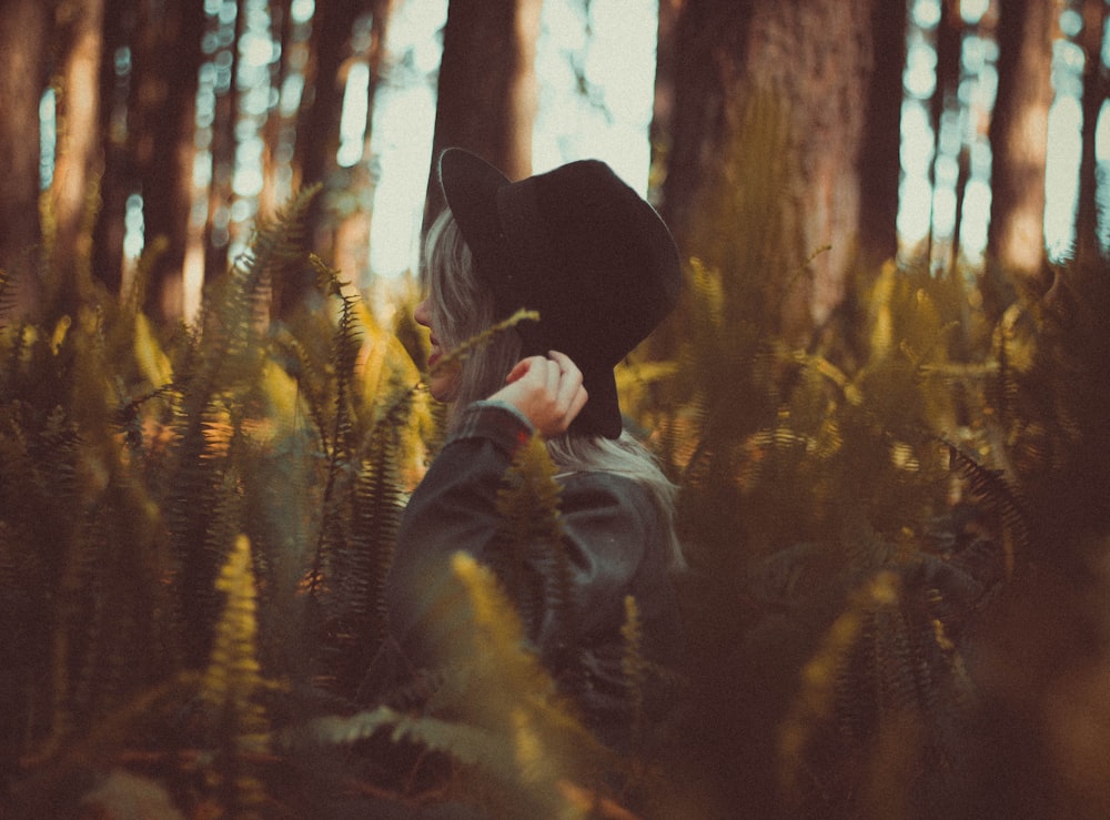 Mujer sosteniendo el sombrero en el bosque durante el día
