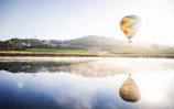 Hot air balloon floating gently above a serene lake reflecting the sky