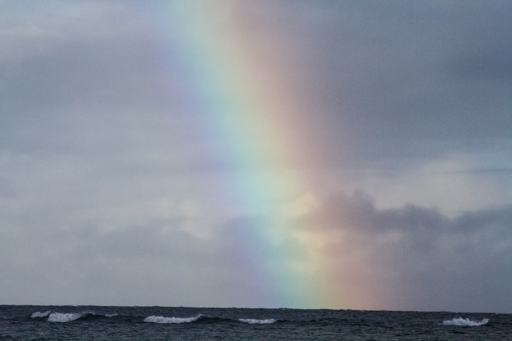 A rainbow shining through a cloudy sky.
