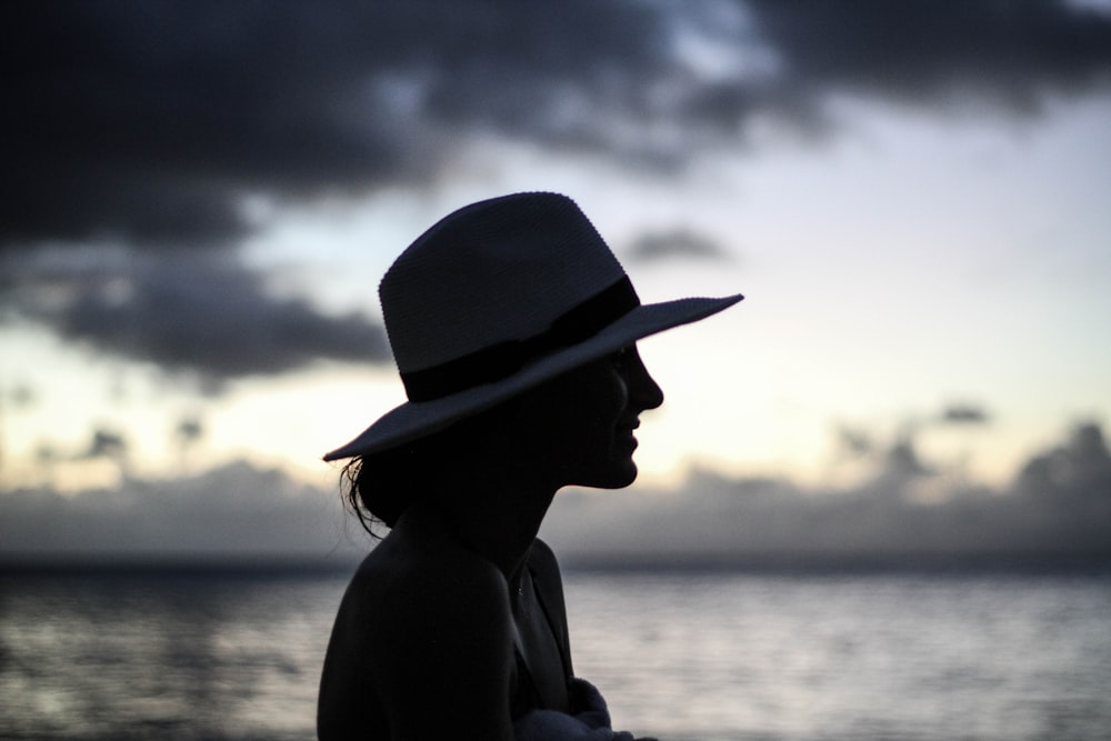 silhouette of woman standing beside body of water