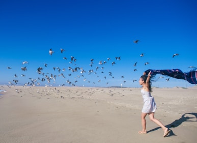 A happy woman jogging along the beach at sunrise, embodying energy and balanced health.