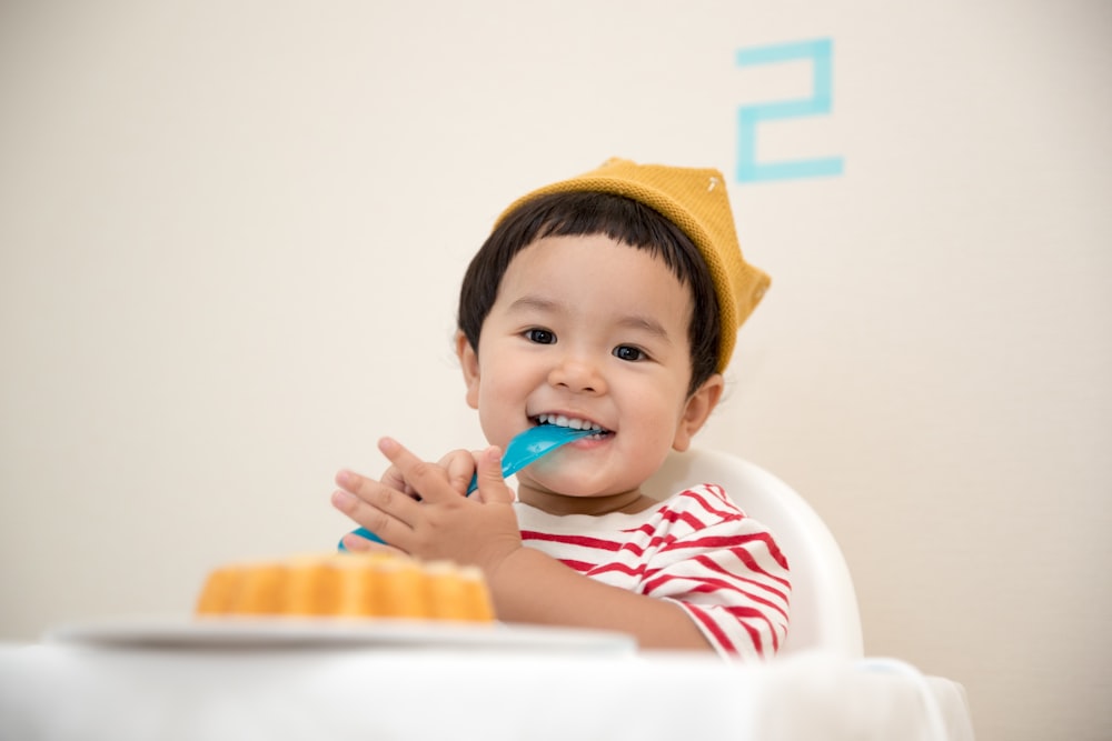 baby sitting on white chair while smiling at the camera