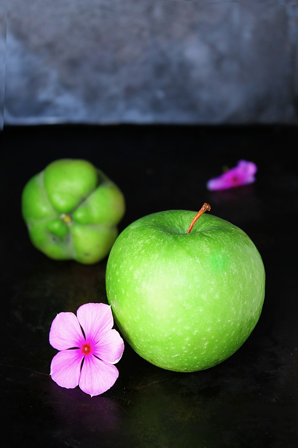 grüner Apfel und rosa Blume