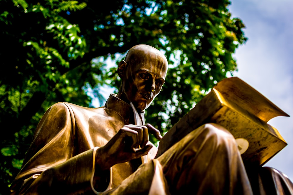 estatua de libro de lectura de hombre de bronce