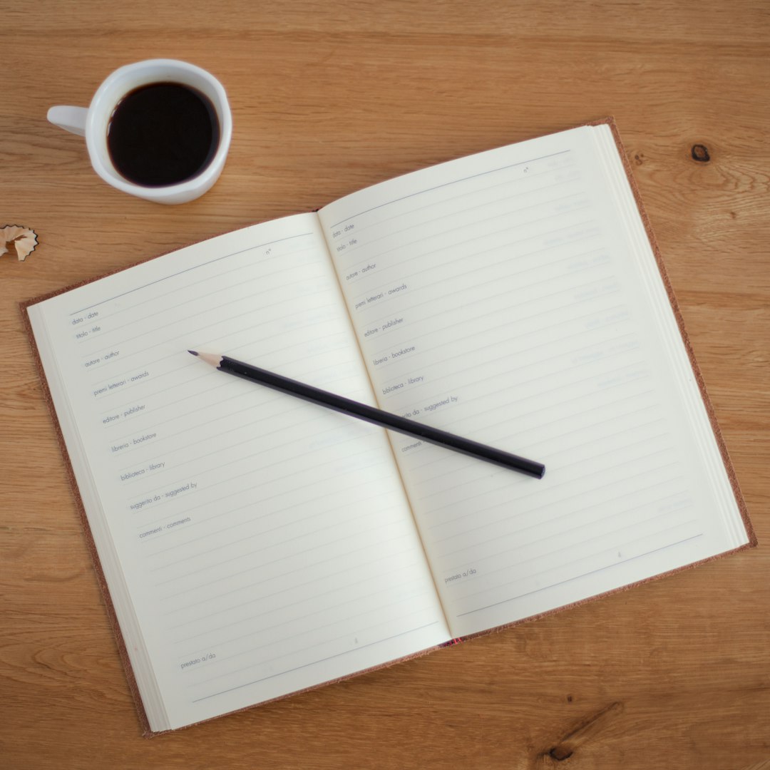 An overhead shot of a pencil on an open planner next to a cup of coffee