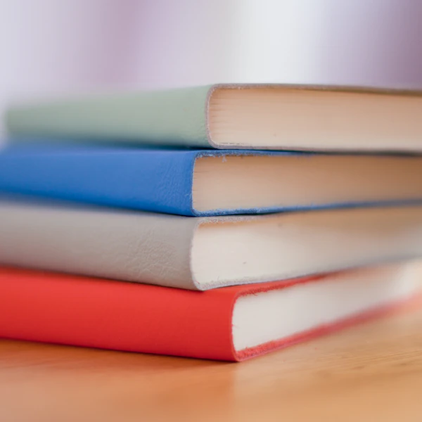 A soft-focus stack of colorful picture books on a wooden table