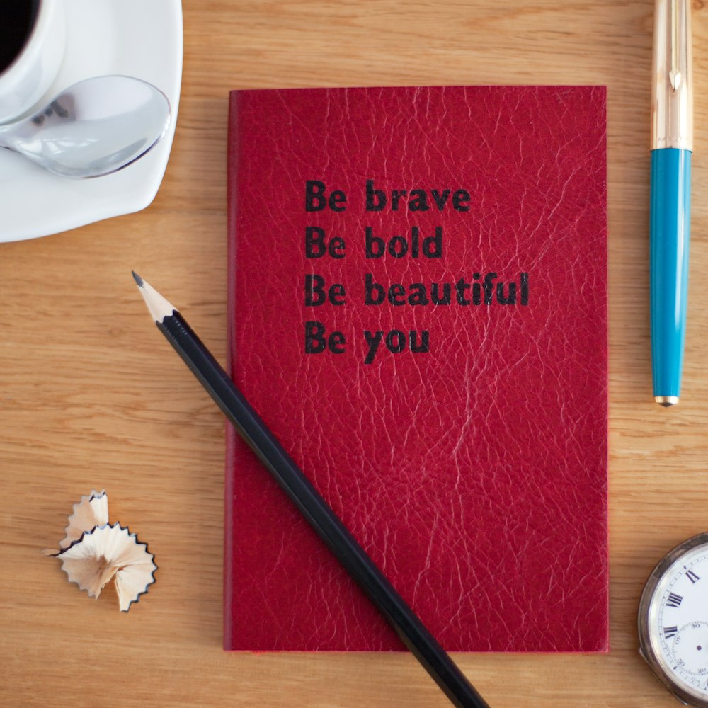 Ein rotes Buch mit schwarzem Titel mit der Aufschrift "Sei mutig Sei mutig Sei schön, sei du selbst".