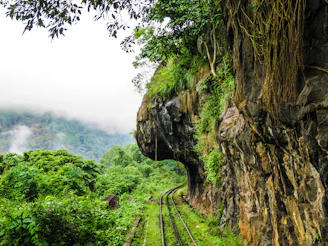 A scenic mountain railway track winding through misty hills.