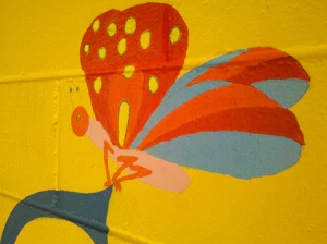 A vibrant urban mural featuring colorful monarch butterflies soaring above a diverse group of young people learning barbering and tattoo art.