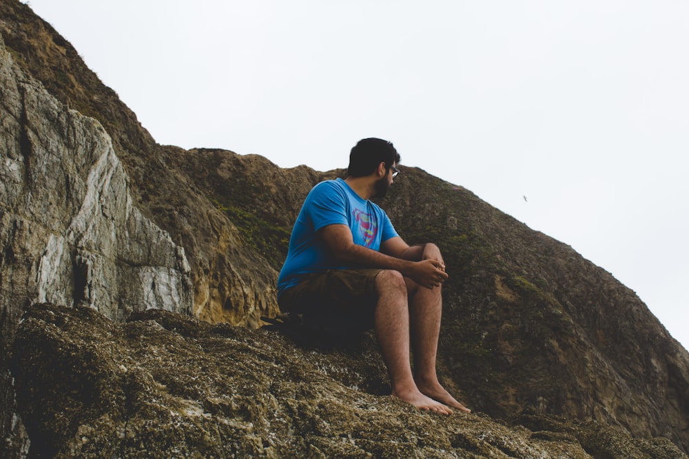 a man sitting on top of a rock next to a mountain