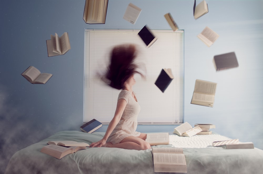 woman sitting on bed with flying books