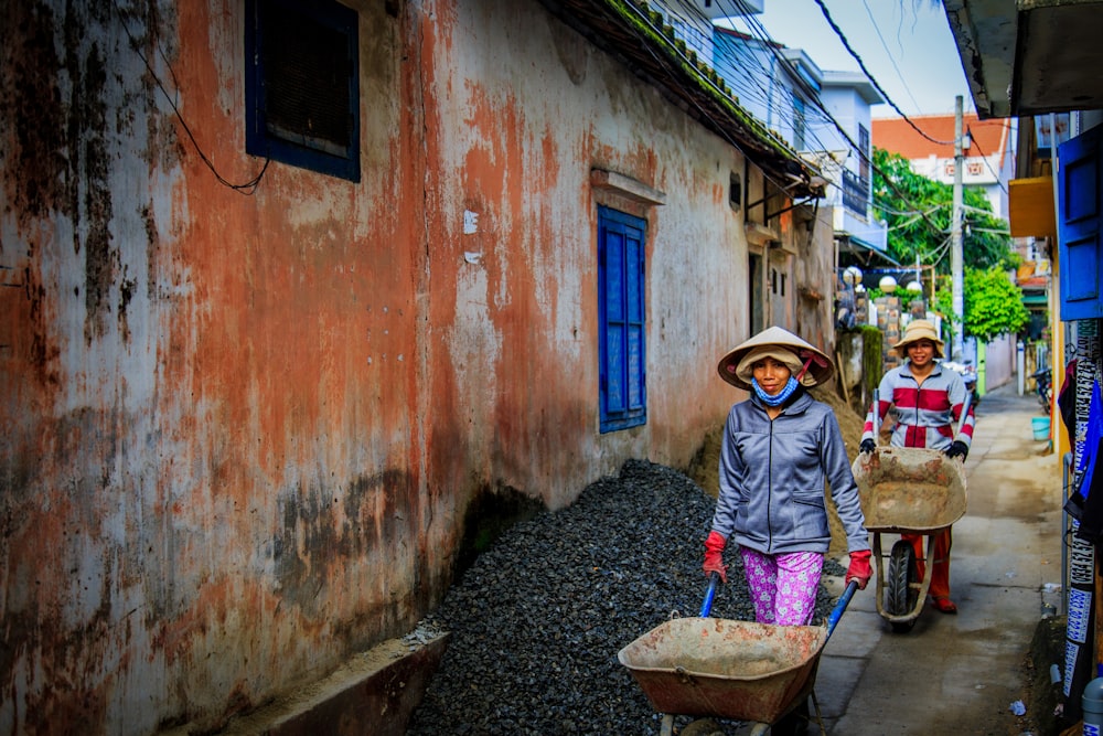 two women walking beside orange house