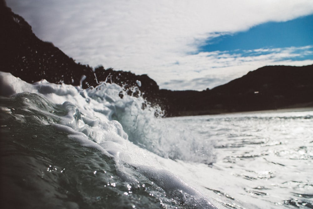 seawaves near mountain at daytime