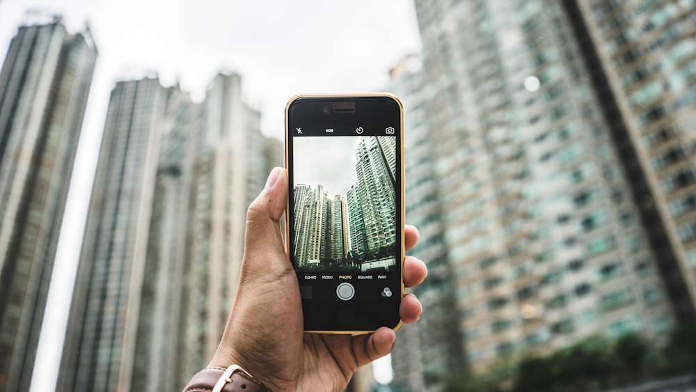 person using smartphone taking picture of building