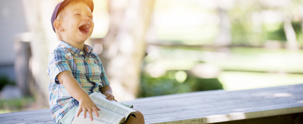 boy sitting on bench while holding a book